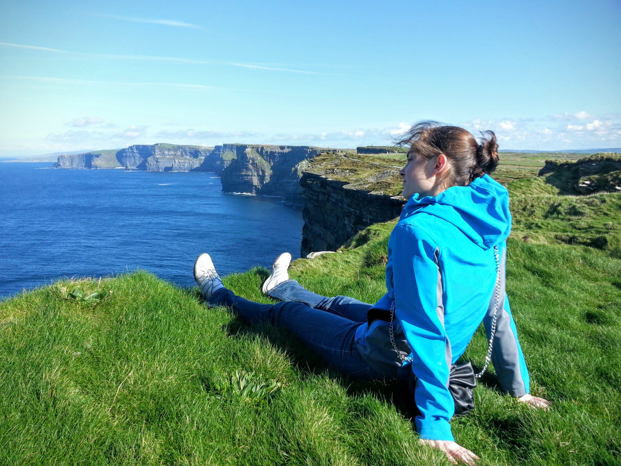 Boise travel agent, Jen Lowry, sits on the grass overlooking the Cliffs of Moher